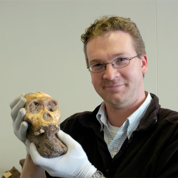 jeremy desilva holding a skull fossil